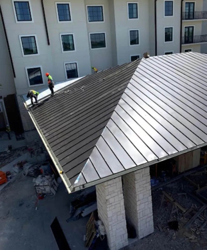 Crew installing standing seam metal roof panels on a commercial project in Mount Hope